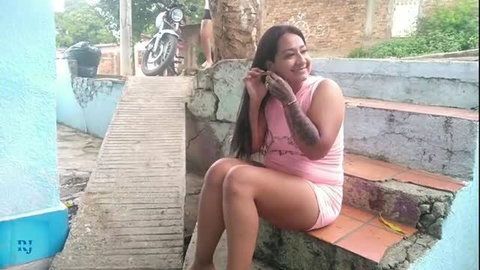 Curvy Latina in pink mini dress posing outdoors on steps