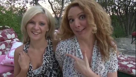 Two mature lesbian blondes smiling outdoors in summer tops