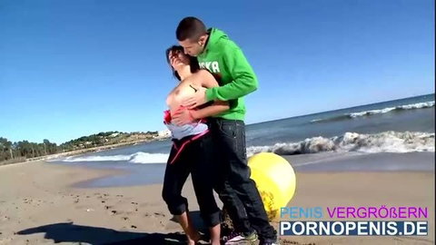 Couple kissing passionately on beach with exposed breasts