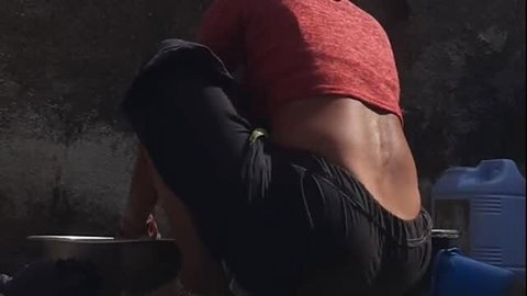 Desi Stepsister bathing outdoors, back view in red top and black bottoms