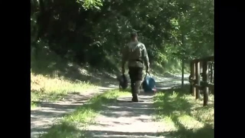 Man walking away down forest path carrying bags