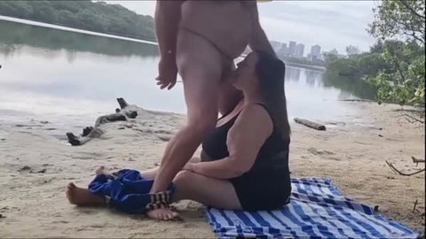 Woman giving oral outdoors by the river on the sand