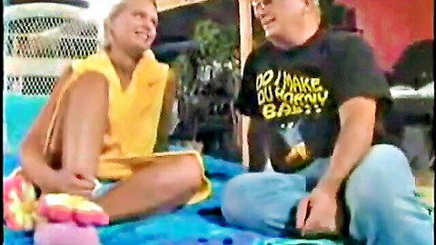 Blonde Keegan Skyy in yellow dress smiles with man on blanket