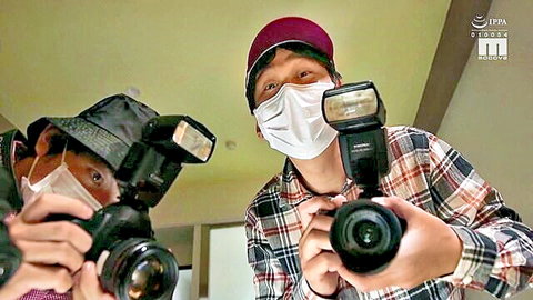 Two masked Asian men photographing each other with cameras and flashes
