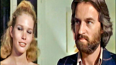Blonde woman in low-cut dress seduces bearded man in suit from Le Droit De Cuissage