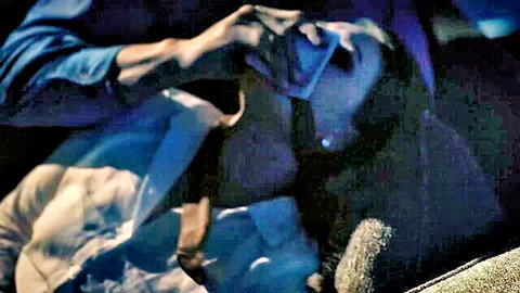 Intimate close-up of man holding brunette woman's face in dim blue light, passionate embrace