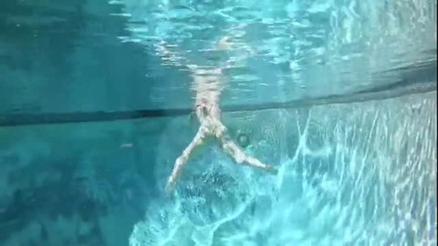 Underwater pool view of nude swimmer with legs spread