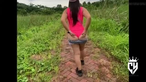 Curvy woman pulling down shorts outdoors, ass exposed on brick path
