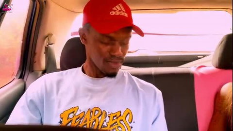 Black male in red Adidas cap and Fearless shirt sitting in car