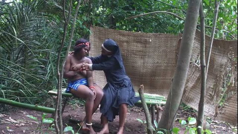 European missionary in nun habit dominating shirtless dark skinned slave outdoors