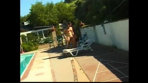 Naked man receives oral outdoors by the pool