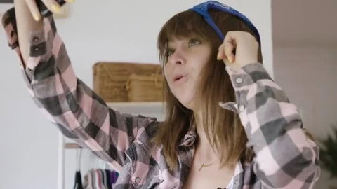 Riley Reid in plaid shirt and bandana, topless, looking up while holding object