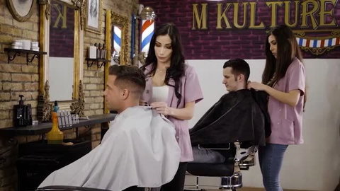 Two female hairdressers in pink uniforms preparing male clients