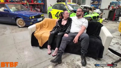 Lexi Angel in leather outfit with man on couch in garage