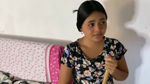 Tina Nandi as new maid holding a wooden stick indoors