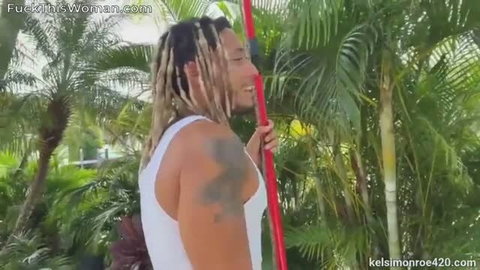 Kelsi Monroe in white tank top with BBC performer in tropical setting