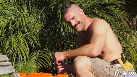 Shirtless muscular man with mustache working outdoors in tool belt