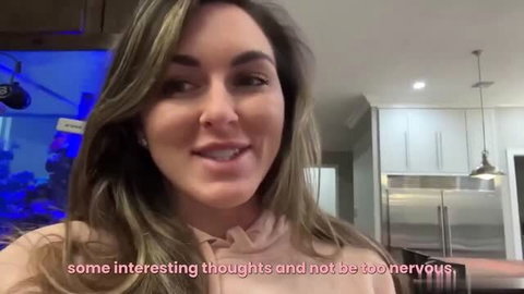 Britt Fit in kitchen selfie, smiling in beige hoodie