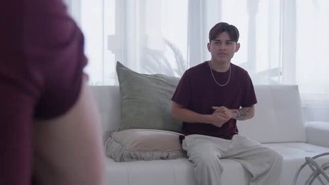 Ella Reese sits on white couch in maroon t-shirt for lucky fan sex scene