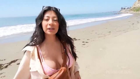 Cami Strella walking beach in pink bikini top and jacket, sunny day
