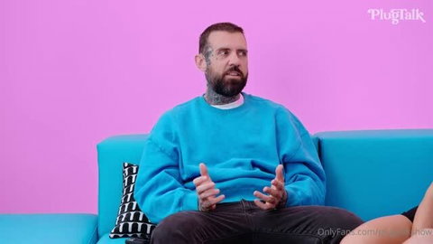 PlugTalk interview with tattooed man in blue sweatshirt on bright pink background