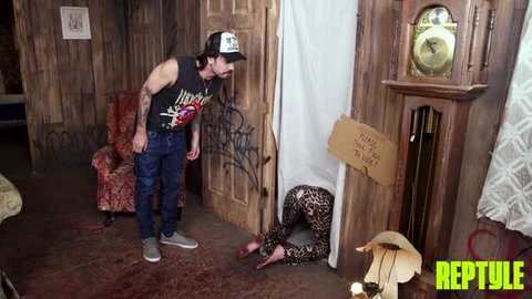 Jessica Aaren in leopard print leggings crawling, tattooed man standing over her in rundown room