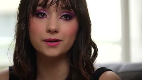 Brunette woman with purple eyeshadow and pink lips closeup