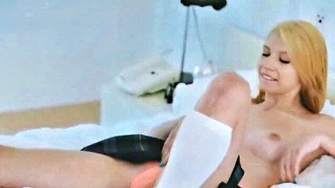 Blonde high school teen topless in plaid skirt and socks, smiling on bed