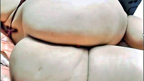 Close-up of curvy woman's large pale buttocks with red straps