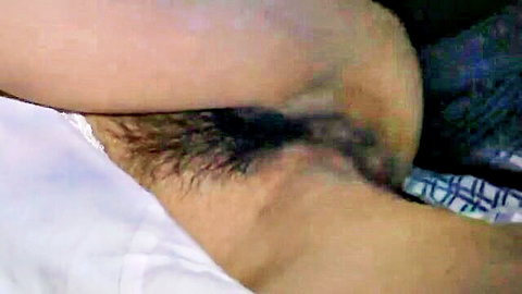 Close-up of East Asian woman's bushy hairy armpit and exposed side tit on bed