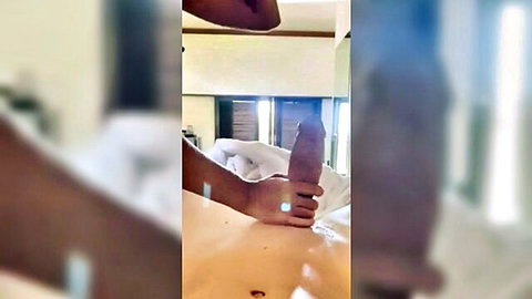 Black hand gripping massive erect black cock on white bedsheet closeup