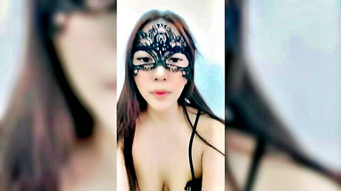 Mysterious Asian woman in black lace mask and lingerie, teasing cleavage