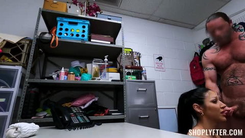 Queenie Sateen on knees giving blowjob to tattooed man in shoplyfter scene