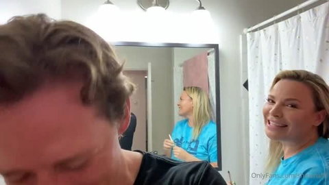 Dana DeArmond in blue shirt taking selfie in bathroom mirror