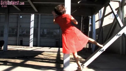 Woman in red polka dot dress posing on metal stairs outdoors