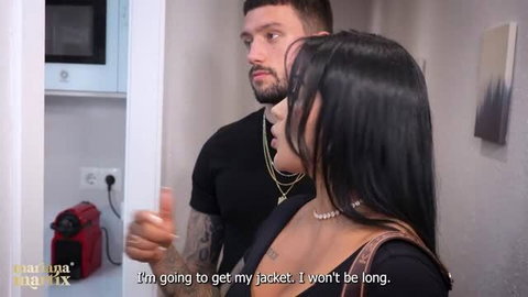 Brunette woman in black top stands close with tattooed man in hallway