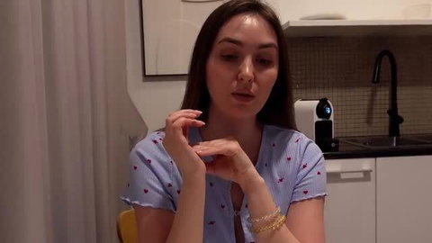Alina Rai in blue heart-print top, sitting in kitchen