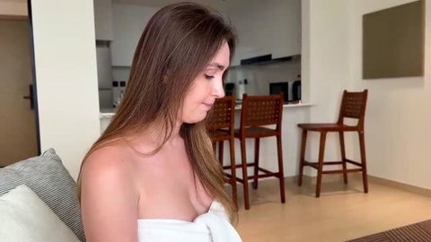 Alina Rai topless with white towel around chest, long brown hair, soft natural lighting