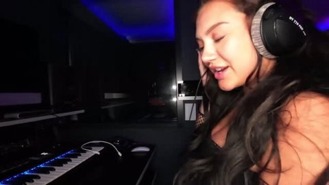 Kylie Jones wearing headphones in music studio, long dark hair, cleavage