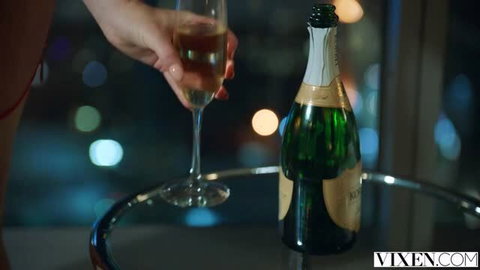 Sophie Dee holding champagne glass in seductive red lingerie pose