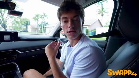 Young man in white t-shirt gesturing from car passenger seat