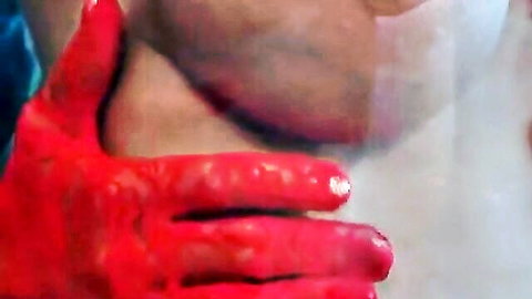 Close-up hand gripping nude breast with red liquid in promo video