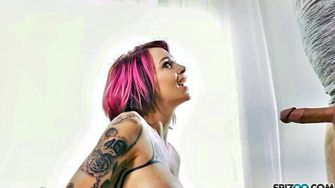 Anna Bell Peaks pink-haired tattooed babe smiling up at cock in blowjob scene