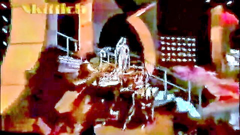 Blurry nude woman with visible tits dances on colorful stage under arch