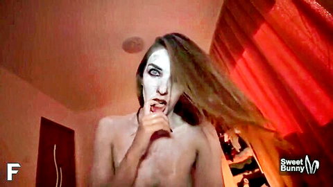 Gothic woman with vampire makeup, nude torso in red-lit seductive pose