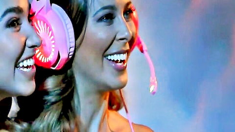 Two sexy blonde gamer girls smiling with glowing pink headsets on
