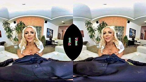 Busty blonde MILF with huge fake tits out kneels in POV VR touching cock bulge on couch