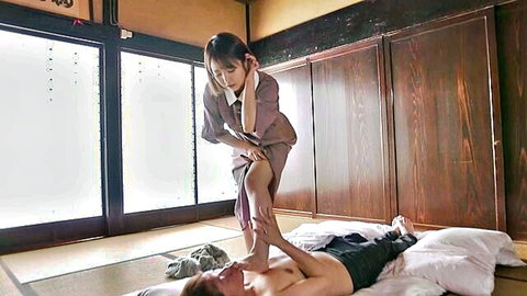 Japanese masseuse in kimono presses bare foot on shirtless man's chest during erotic massage