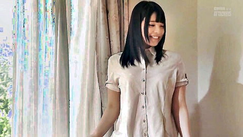 Smiling Japanese beauty in beige button-up shirt posing seductively by window