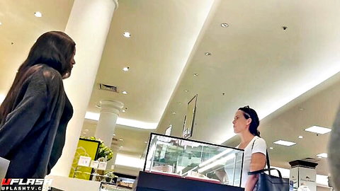 Two Asian women chatting near store counter, bulge watching tease